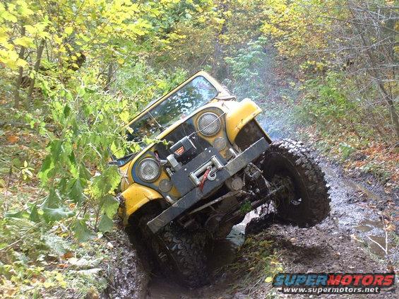 Yellow Jeep CJ stuck in mud on a trail, front winch visible