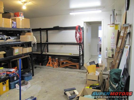 Garage interior with shelves, boxes, water heater, and lumber