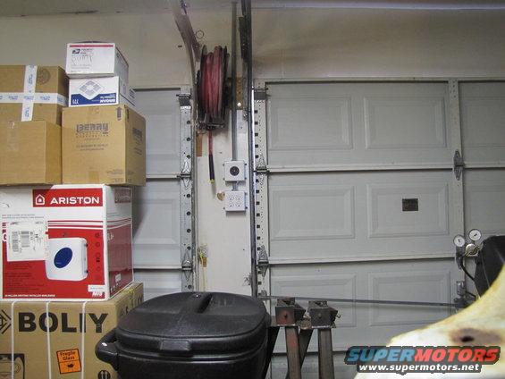 Boxes stacked high, a hose reel, and garage doors in a cluttered garage