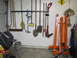 1993 Ford F-250 - A collection of garden tools and a welding machine are organized on a garage wall, with an engine hoist nearby.