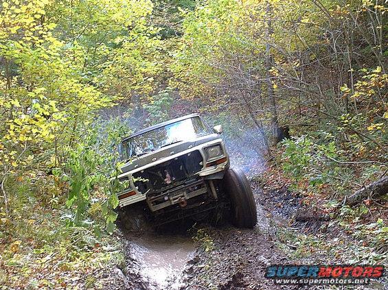1978 Ford Bronco driving through mud, front 3/4 view