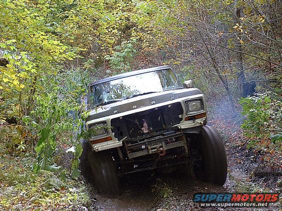 1978 Ford Bronco navigating a muddy trail with smoke coming from the exhaust