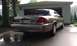 2007 Ford Crown Victoria - The rear of a gold sedan is parked on a wet driveway in front of an open garage door.