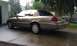 2007 Ford Crown Victoria - A tan 2007 Ford Crown Victoria is parked on a wet driveway next to a garage.