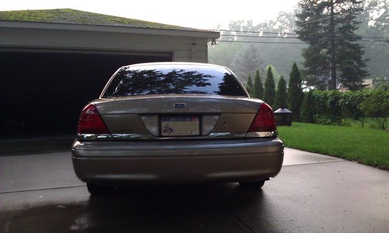 Rear view of a gold 2007 Ford Crown Victoria parked in a driveway