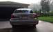 2007 Ford Crown Victoria - The rear of a gold 2007 Ford Crown Victoria is visible, parked in front of a garage with a manicured lawn in the background.