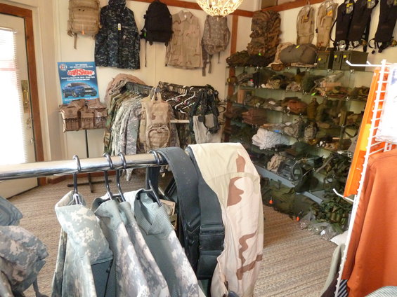 Interior of a military surplus store with camouflage clothing and gear on racks and shelves