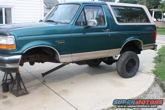 Green 1996 Ford Bronco side view on jack stands, front end raised