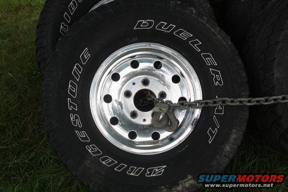 Stack of Bridgestone Dueler A/T tires on chrome wheels, secured with a chain