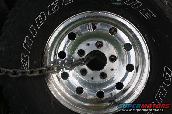 Close-up of a tire with 'BRIDGESTONE' text and a chrome wheel secured by a chain
