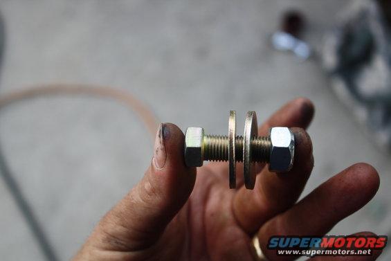 Bolt with two nuts and two washers held by a hand
