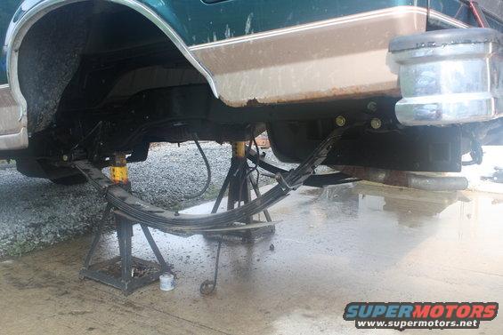 Green and brown 1996 Ford Bronco rear leaf spring suspension on jack stands