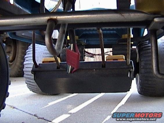 Underside of a lawn mower deck with exhaust pipe and wheels visible