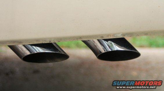 Two chrome exhaust tips angled downwards, attached to a cream-colored vehicle
