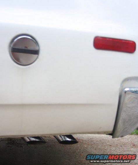 White vehicle rear with dual exhaust tips and chrome bumper detail