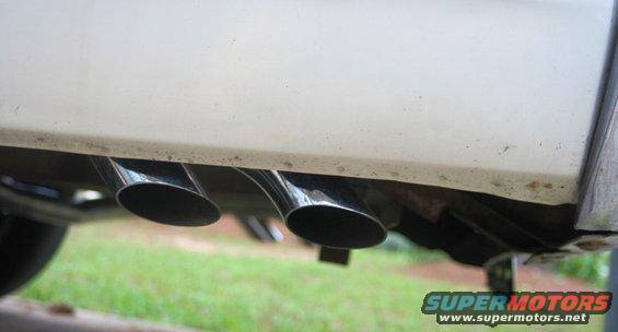 Close-up of dual chrome exhaust tips exiting the rear of a white vehicle