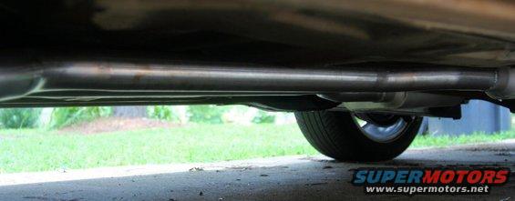 Underside view of a car's exhaust pipe and muffler, with a wheel visible