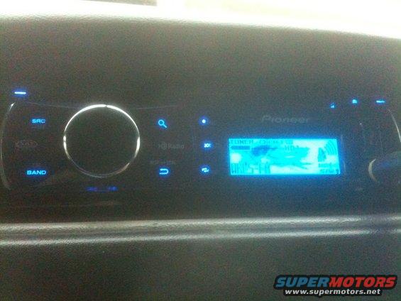 Car dashboard with a Pioneer stereo displaying a blue screen with text and graphics