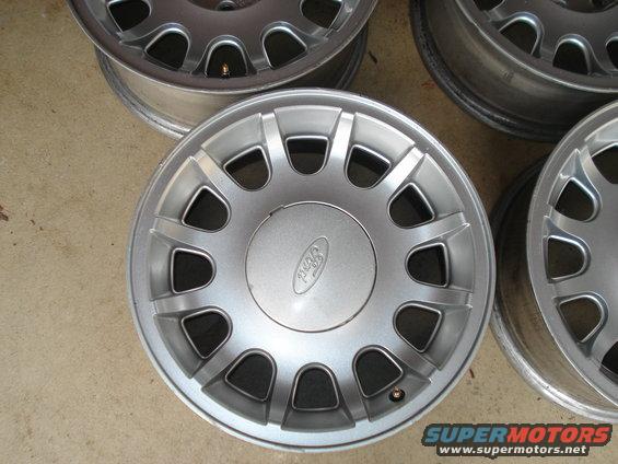 Four silver Ford wheels with a Ford logo on the center cap