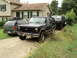 1986 Ford Bronco - Three SUVs are parked in a driveway in front of a house, with the middle vehicle being a black Ford Bronco.