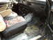 1986 Ford Bronco - The interior of a vehicle shows a dirty floor and camouflage seat covers.