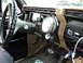 1986 Ford Bronco - The dashboard of an older truck features a large steering wheel and several aftermarket gauges, including a prominent tachometer.