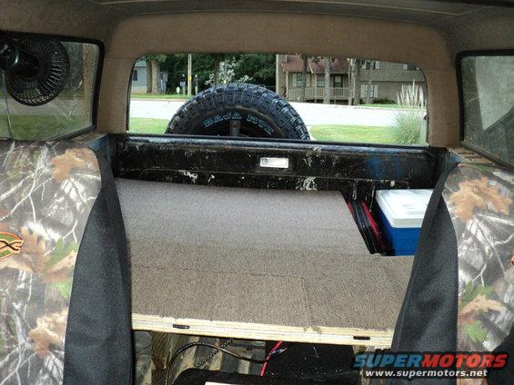 Interior view of a 1986 Ford Bronco showing a spare tire and camouflage seat covers