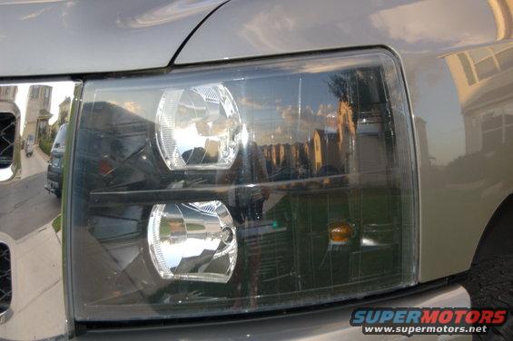 Front view of a blacked-out headlight on a light-colored truck