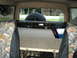 1986 Ford Bronco - The interior of a vehicle shows camouflage seat covers and a spare tire visible through the rear window.