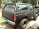 1986 Ford Bronco - This 1986 Ford Bronco is shown from the rear three-quarter view, a matte black finish and aggressive off-road tires.