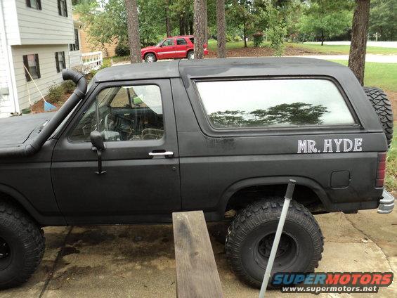 Black Ford Bronco with snorkel and "MR. HYDE" decal. Red SUV in background