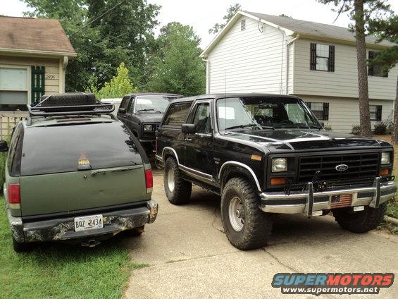 Black Ford Bronco parked next to a green SUV in a driveway