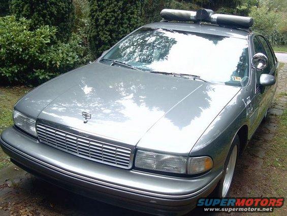 Gray police car with light bar on roof. Looks like a 1991 Chevrolet Caprice