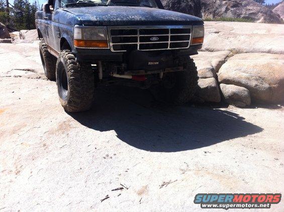 Ford truck with big tires on rocks. Has a Recon winch