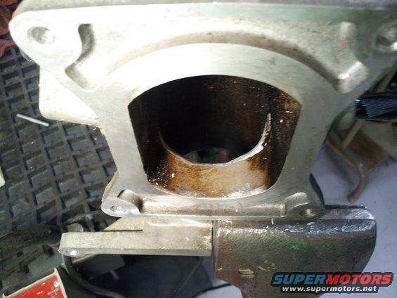 Intake manifold port with carbon buildup, held in a vise