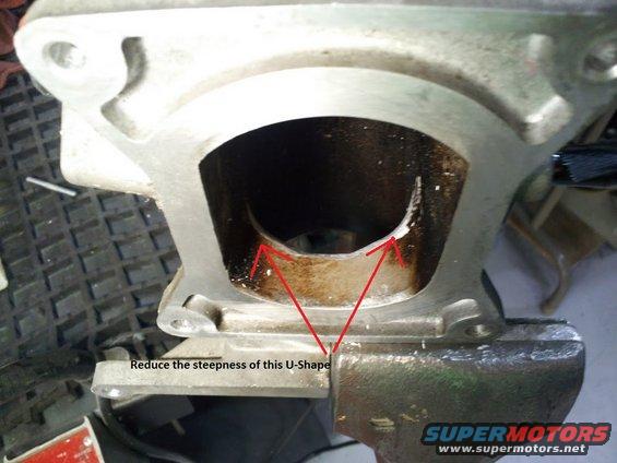 Close-up of an engine intake manifold port with red arrows pointing to the U-shape and text indicating to reduce its steepness. Supermotors.net logo visible