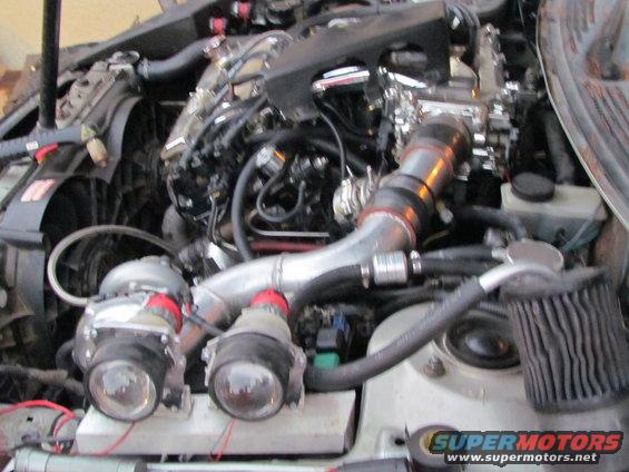 Engine bay with twin turbochargers, intercooler piping, and air filter. Some wiring is visible