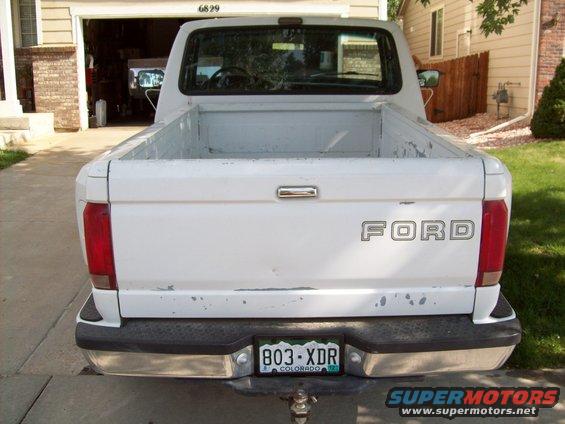 White Ford pickup truck rear view, showing tailgate with FORD lettering and Colorado license plate 803-XDR