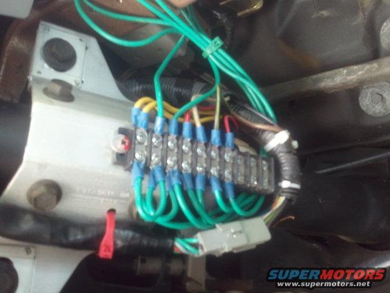 Close-up of a vehicle's wiring harness and fuse block with blue-tipped connectors