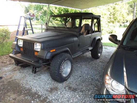 Black 1993 Jeep YJ parked under a carport next to another vehicle