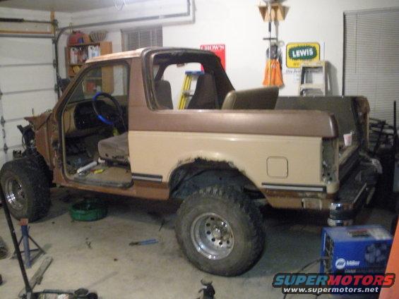 1987 Ford Bronco with doors removed, sitting on jack stands in a garage