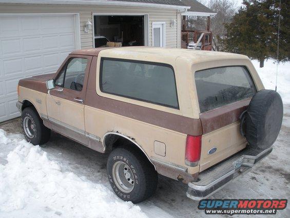 Two-tone brown and tan SUV parked in snow, spare tire on rear door