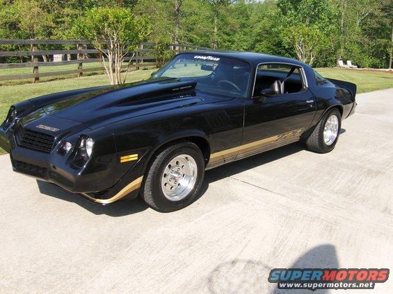 Black Chevrolet Camaro with a large hood scoop and gold Z28 stripe on the side