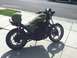 2002 Kawasaki Ninja - A green motorcycle with a green helmet resting on its seat is parked on a sidewalk.