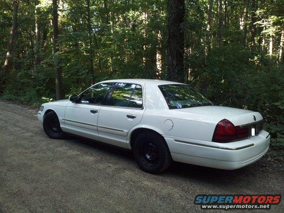 White 2000 Mercury Grand Marquis parked on a dirt road with trees in the background