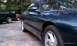 1997 Ford Probe - A dark green coupe is parked on a gravel surface, with other vehicles visible in the background.