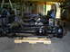 1992 Ford Bronco - Front axle and suspension parts are laid out on a wooden dolly in a garage.