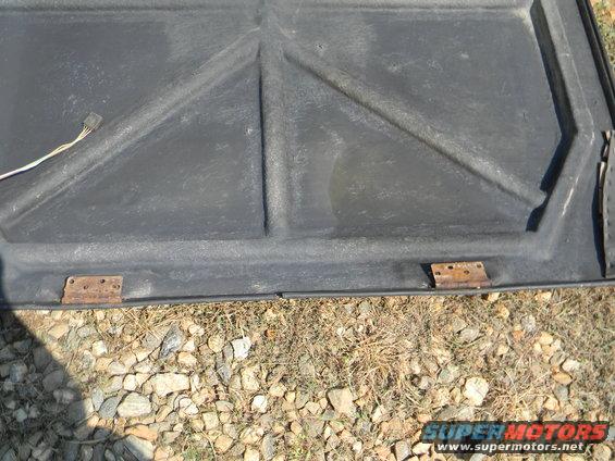 Underside of a car hood showing bracing and hinges. Wire harness visible