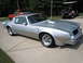 1976 Pontiac Trans Am - A silver 1976 Pontiac Trans Am is parked on a concrete surface, with a red truck and a golf cart in the background.