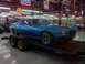 1976 Pontiac Trans Am - A blue muscle car from the 1970s is displayed on a trailer inside a showroom.